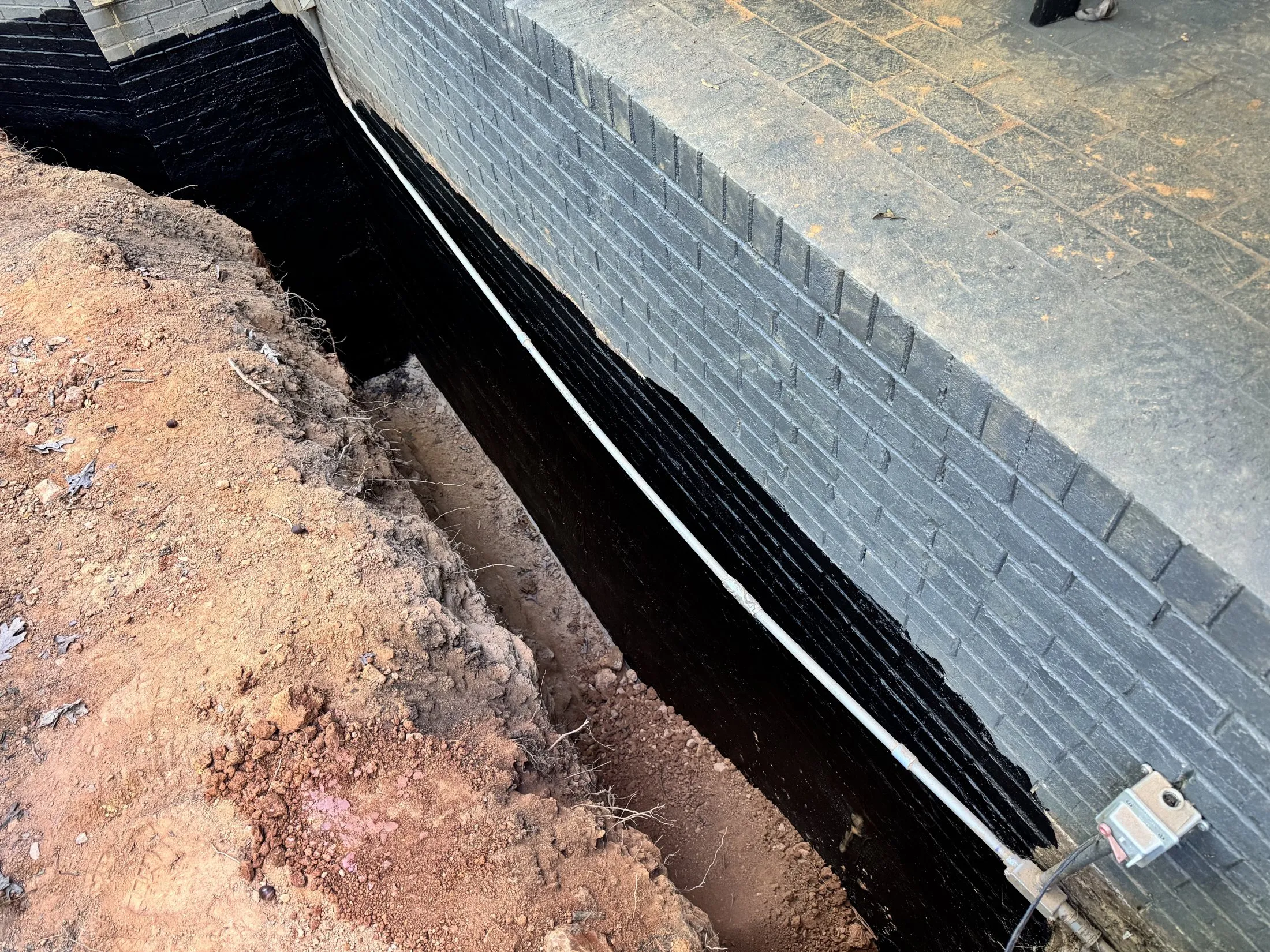 Exterior foundation waterproofing with a black membrane and drainage during a Ballantyne area job