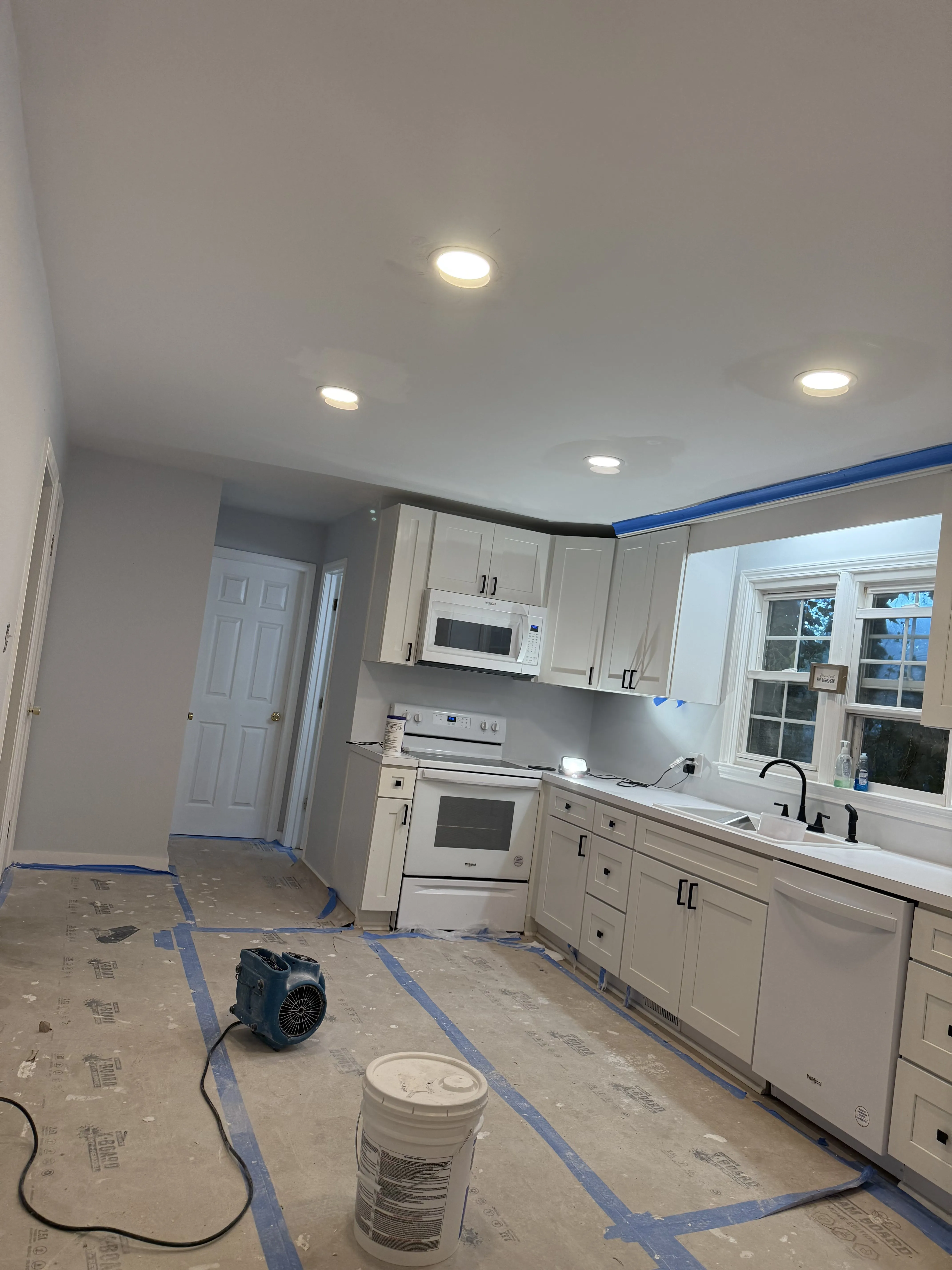 A finished kitchen by Carolina Pro Restoration with white cabinets, new counters, and recessed lighting