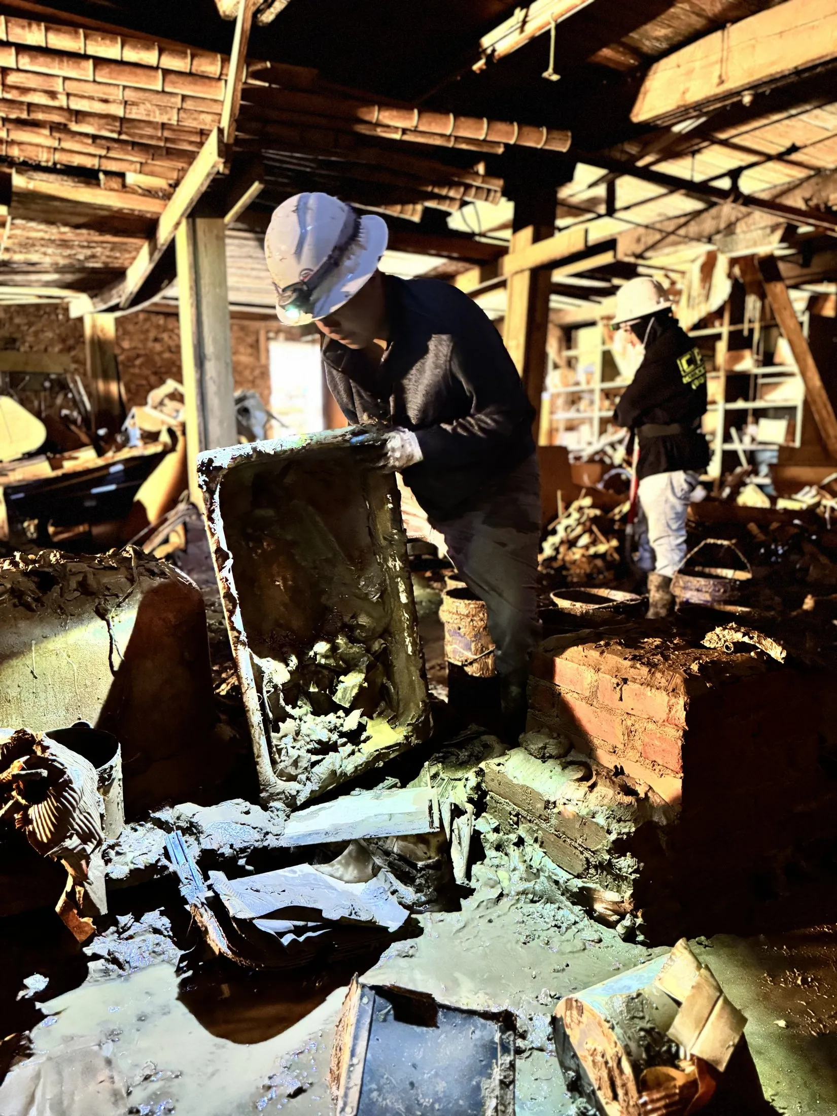 Carolina Pro Restoration technicians in hard hats clearing flood debris from a storm-damaged building